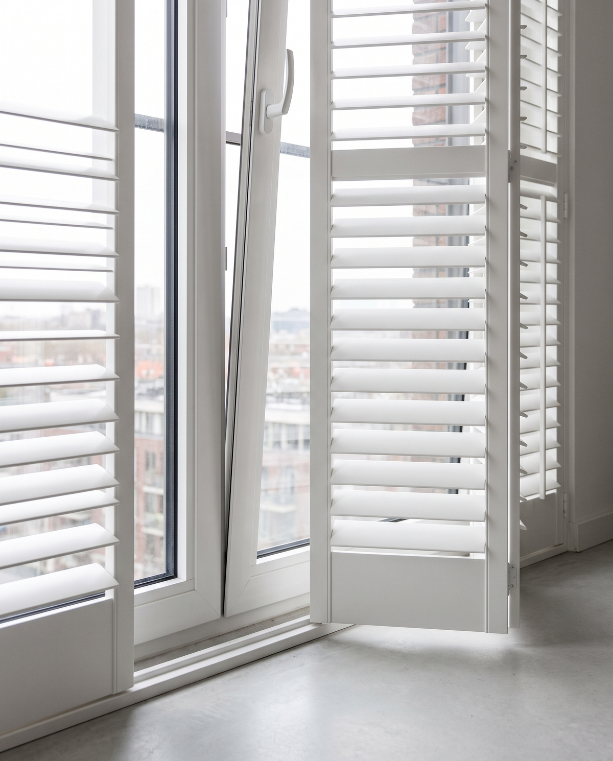 Witte shutters op een draaikiepraam